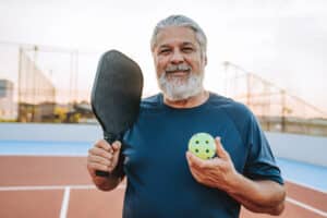 senior man playing pickleball with a heart condition