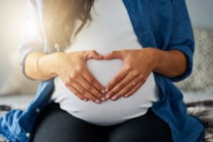 pregnant woman making a heart symbol on her belly