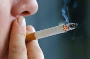 person smoking a cigarette, which increases the risk of heart disease