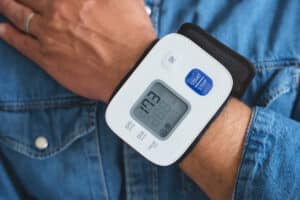 Man checking his blood pressure with a digital wrist monitor during a heart disease risk assessment